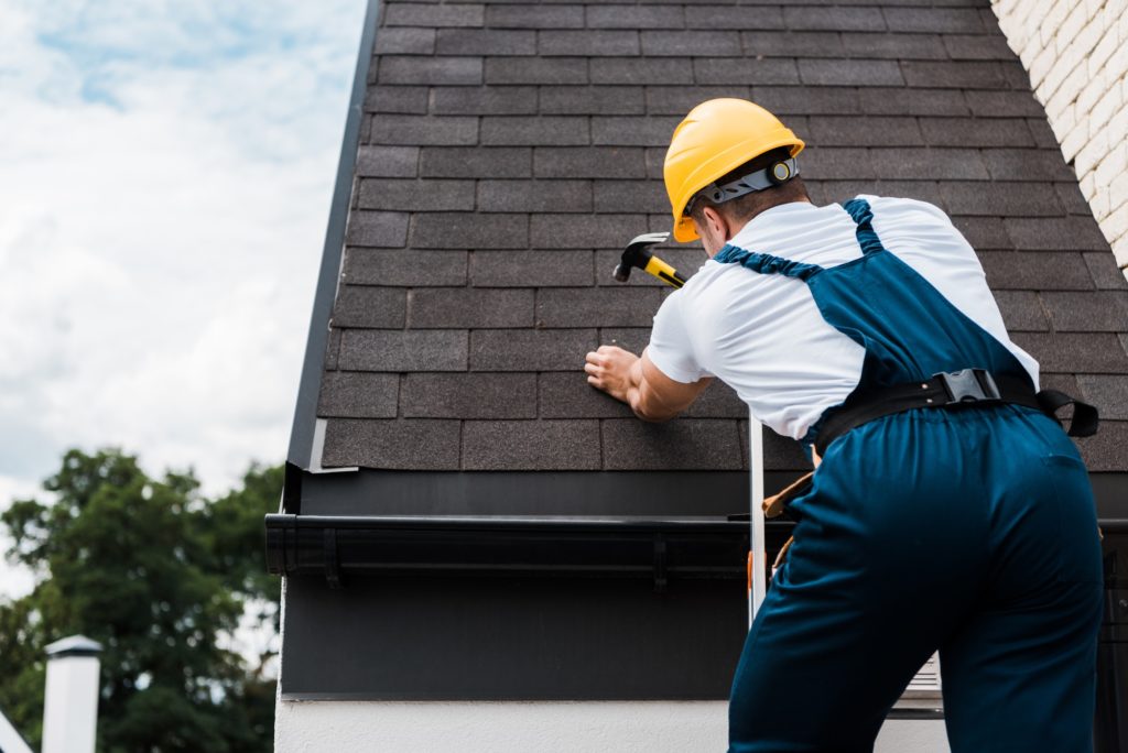 Man nailing shingles to roof - the best roofing crews needed in Texas