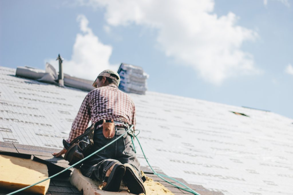 Man on roof replacing shingles
