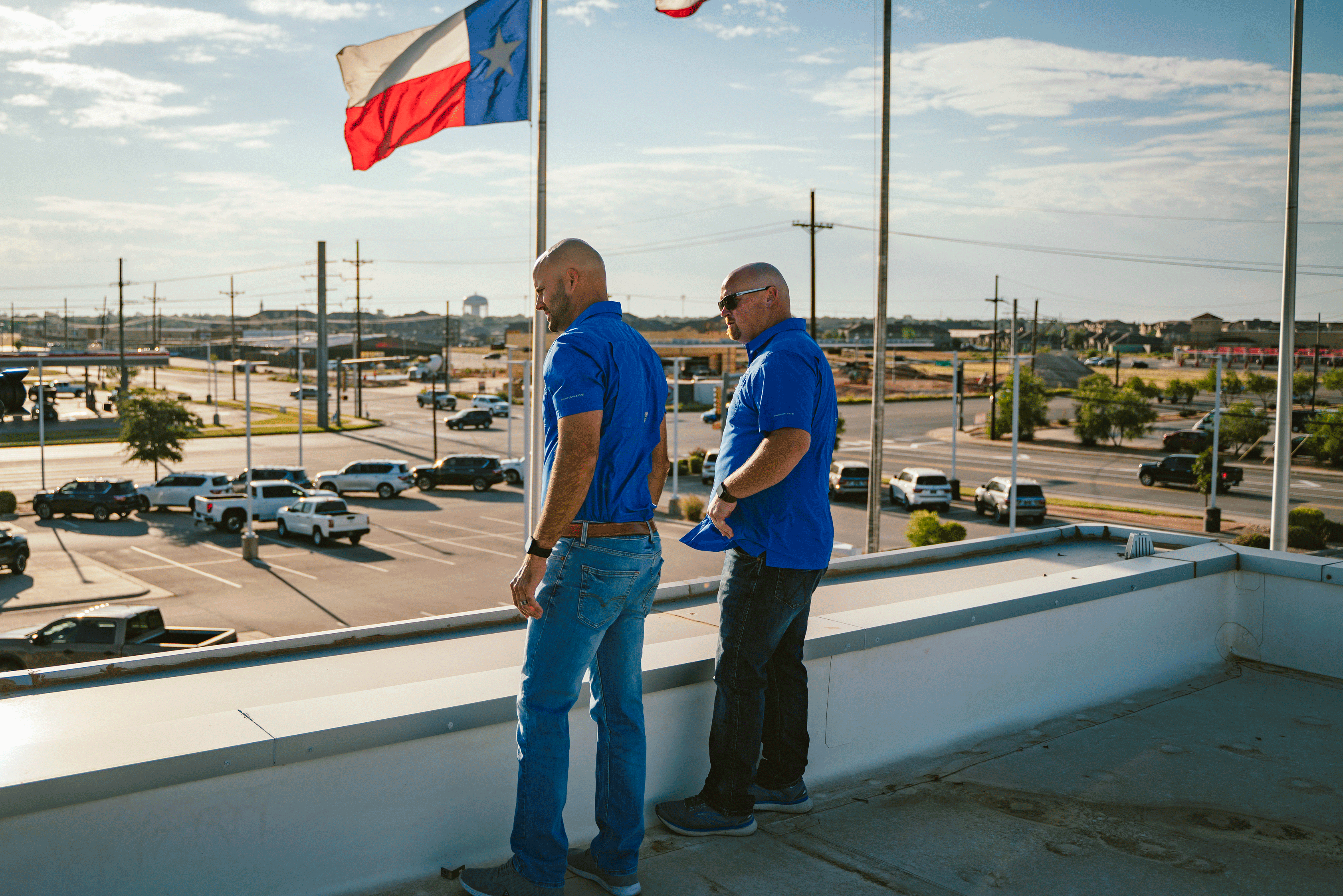 Two men inspecting a roof with Texas flag behind them.