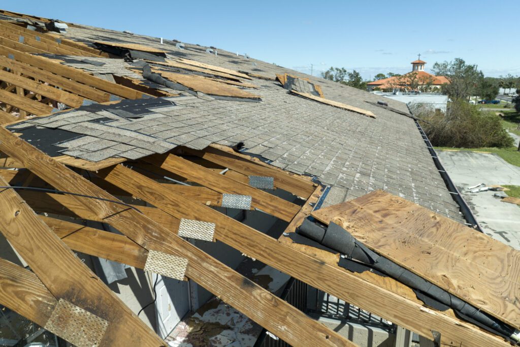 Severe wind and storm damage on a shingle roof, exposing wooden trusses and highlighting common roofing problems in West Texas that require emergency roof repairs.