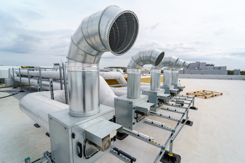 Industrial roof ventilation system with multiple large duct vents installed on a flat commercial roof, showcasing a modern roof ventilation setup.