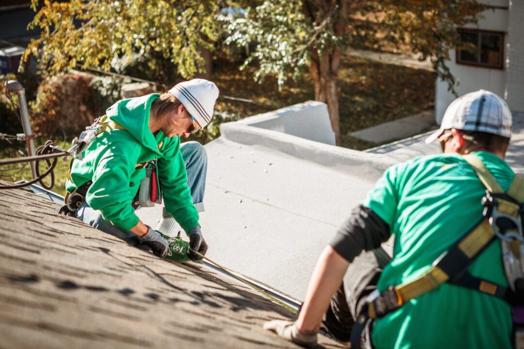 Solar panel installation crew members on roof of house Roof Repair vs. Replacement - West Texas Commercial Roofing